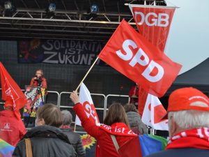 Demonstration 1. Mai. Sascha Aulepp hält eine SPD-Fahne hoch.